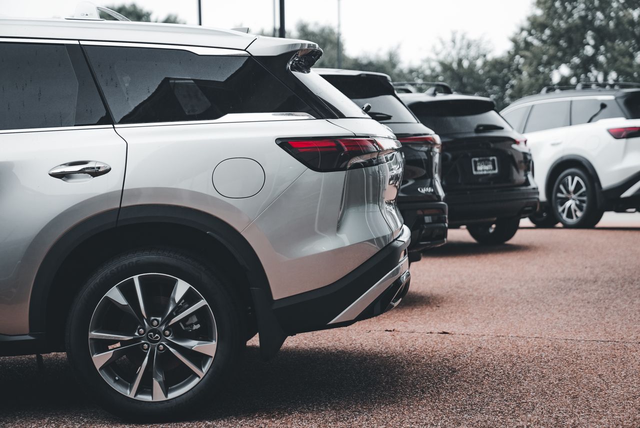 A row of parked SUVs including a silver Infiniti QX60 in an outdoor setting.