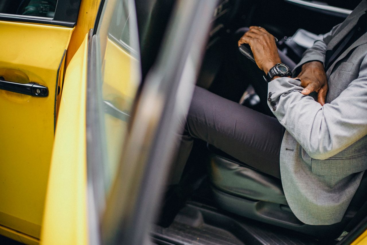 Side view of crop anonymous African American male in elegant suit checking wristwatch in car